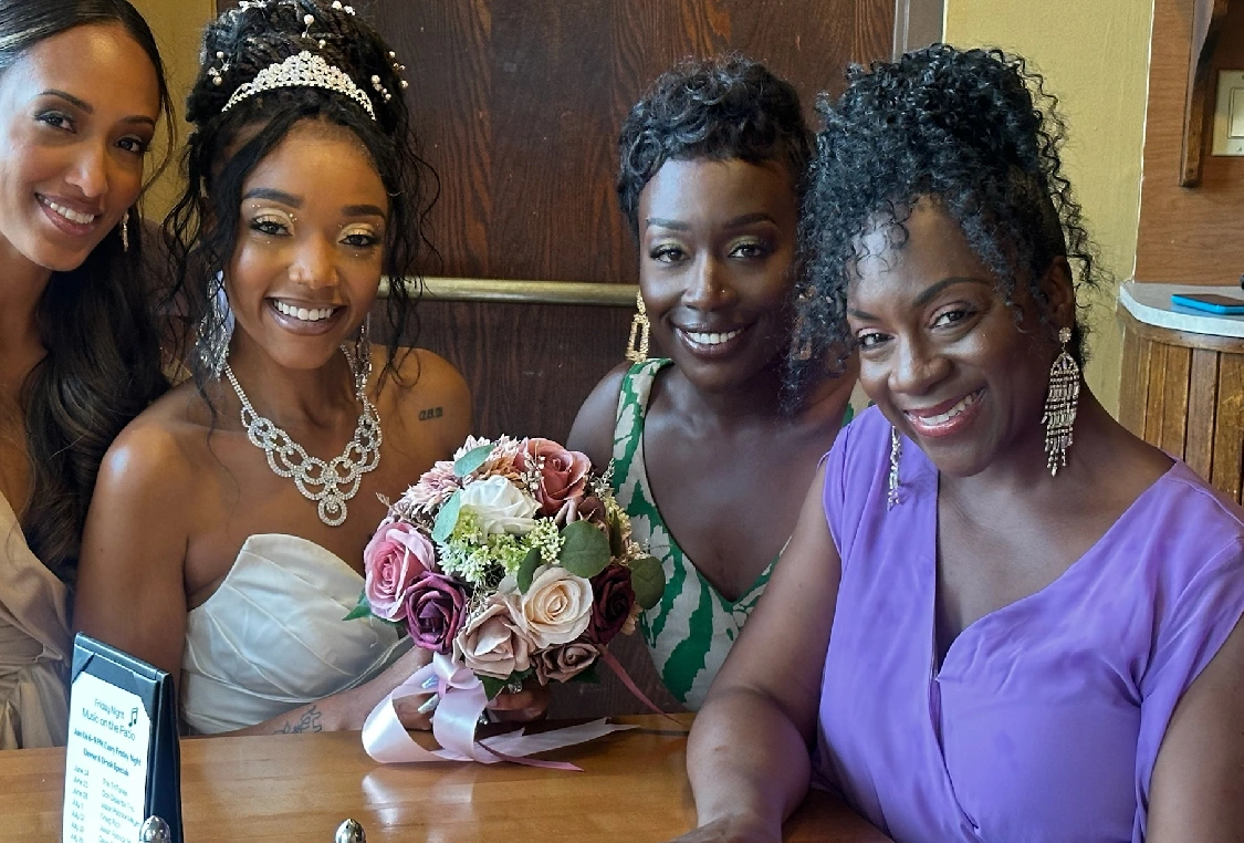 Three women sitting at a table with a bouquet of flowers.